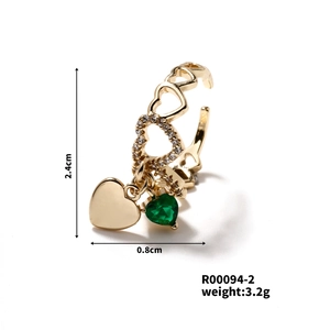 Detail of gold heart ring with green gemstone charm and inlaid cubic zirconia stones