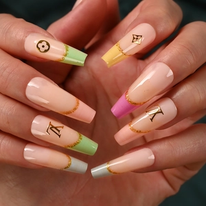 Macro detail of long French manicured nails with gold monogram patterns and brand logo