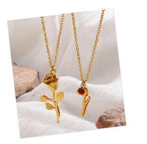 Detail view of gold rose necklace set with red gemstone pendant on white silk background