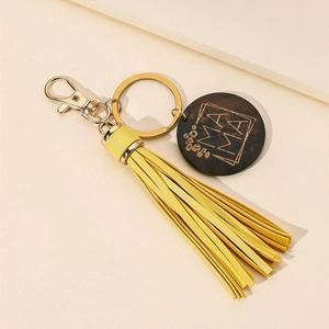 Close-up of yellow PU fringe tassel and engraved MAMA wooden pendant on golden keychain