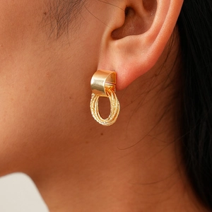 Close-up of golden multi-loop earrings with matte texture shown on model's ear