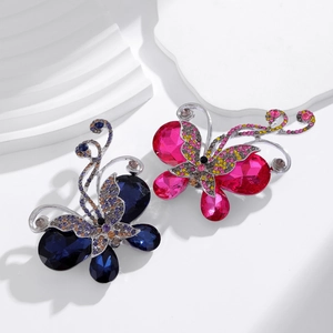 Elegant butterfly crystal brooches in blue and pink on modern stone display