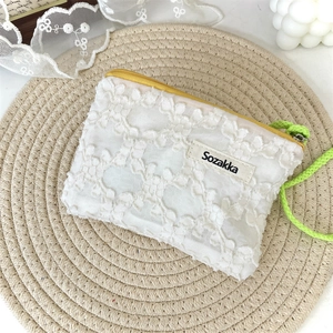 Détail de la pochette en dentelle florale blanche avec cordon fluo et zip jaune vif