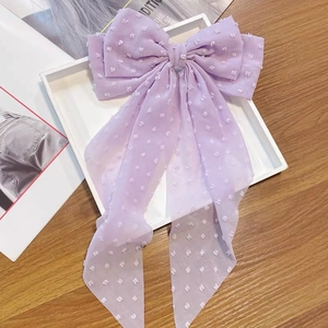 Close-up of lavender chiffon bow hair clip with white polka dot texture and long tassels