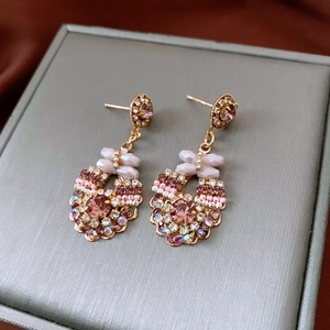 Close-up of vintage gold earrings with pink crystals and intricate floral beadwork