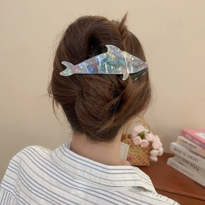 Close-up of a gradient dolphin claw clip with iridescent finish on a hair bun