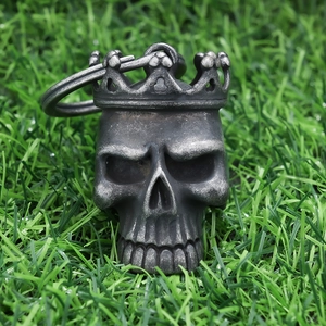 Close-up of vintage silver skull with crown pendant on realistic green grass background