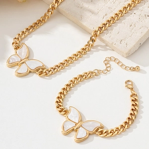 Detail of gold butterfly pendant necklace and bracelet set on stone background