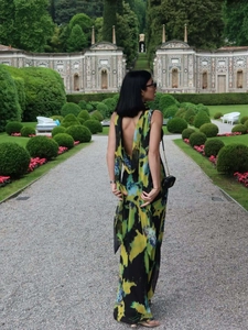 Détail de la robe maxi dos nu avec imprimé abstrait vert et jaune dans un jardin
