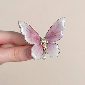 Detailed close-up of butterfly hair clip with pink gradient resin and pearl pendant