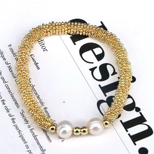 Close-up of golden beaded bracelet featuring white pearls and delicate metallic accents