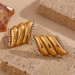 Dettaglio macro di orecchini a spirale placcati oro 18K con pavé di zirconi bianchi