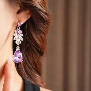 Detail of vintage silver earring with purple zircon flower and pear-shaped droplet