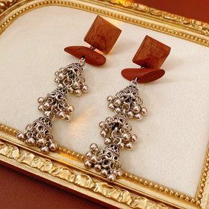 Detail of silver wood tiered bell earrings with bohemian ethnic tassel design