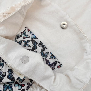 Close-up of magnetic snap closure and colorful butterfly print lining on canvas tote bag