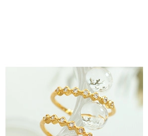 Macro shot of gold-plated wave rings featuring clear round-cut cubic zirconia gemstones