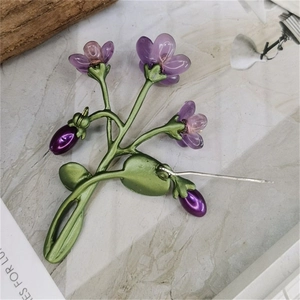 Violet flower brooch with green leaves and freshwater pearls on marble surface