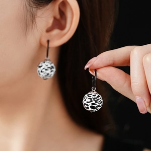 Detail shot of leopard print spherical earrings worn to show the high-end texture and style