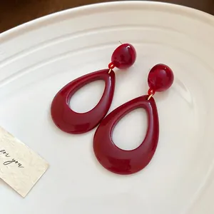 Vintage burgundy resin teardrop cutout earrings with silver needles on ceramic tray