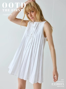 Détail d'une robe mini plissée sans manches blanche avec décolleté à nouer et texture en lin
