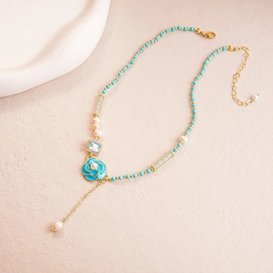 Elegant beaded necklace featuring blue flowers and pearls with a gold lobster clasp
