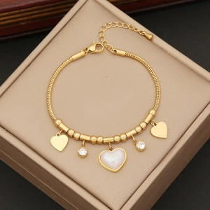 Elegant gold snake chain necklace featuring pearl heart charms and zircon stones on a box
