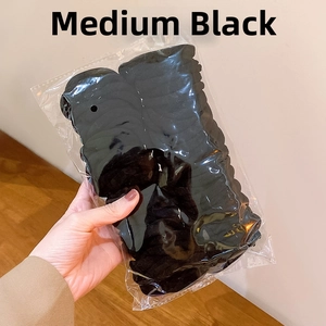 Detailed macro view of medium black elastic scrunchies set in clear packaging