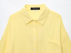 Close-up of yellow cotton linen shirt with white buttons and double gauze texture details