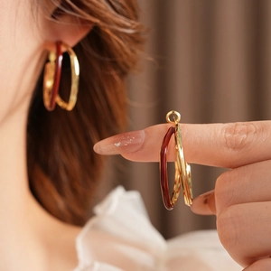 Close-up of double hoop earrings in gold and burgundy finish worn by a model