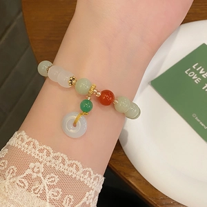 Detail of beaded jade bracelet with blue Ping'an Kou pendant on model wrist