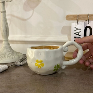 Detail of hand-painted floral ceramic coffee cup in a vintage aesthetic lifestyle setting