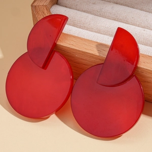 Detailed close-up of red acrylic geometric round earrings on a wooden display tray