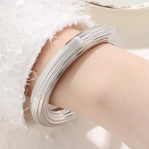 Gros plan d'un bracelet jonc large en acier inoxydable argenté rayé pour femme