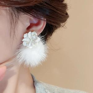 Gros plan de boucles d'oreilles fleurs blanches avec pompon en fausse fourrure