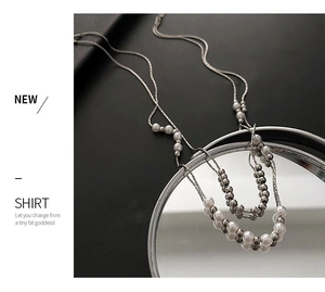 Close-up of double-layered pearl and titanium steel necklace reflected on a mirror
