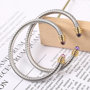 Detailed macro view of two-tone cable cuff bracelets with colored gemstone settings