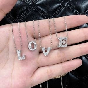 Macro view of four silver zircon LOVE letter pendants held by hand on black leather