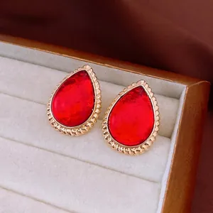 Vintage gold teardrop earrings featuring a large red resin stone and twisted rope metal border