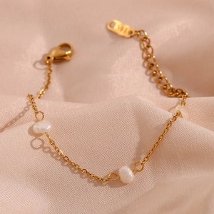 Detail of gold chain bracelet with white pearls and adjustable clasp on pink silk