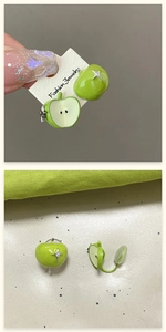 Detailed view of asymmetric green enamel apple stud earrings with sparkling crystal accents