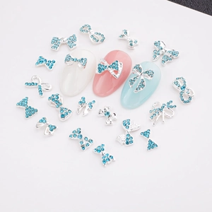 Vue macro de bijoux d'ongles en nœud argenté avec strass bleu clair sur ongles soignés