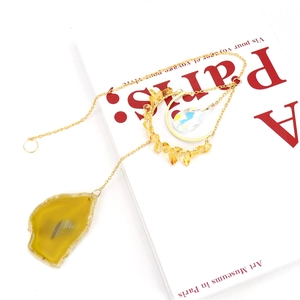 Natural agate slice and yellow crystal suncatcher with golden moon pendant on a Paris art book