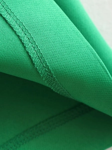 Vue détaillée de la texture du tissu vert avec couture double de haute qualité sur la robe
