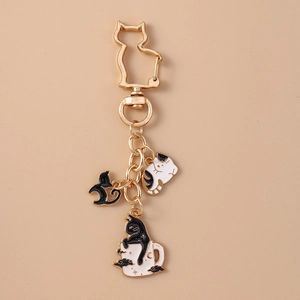 Detail of cute cat charms featuring black and white kittens on a gold keychain