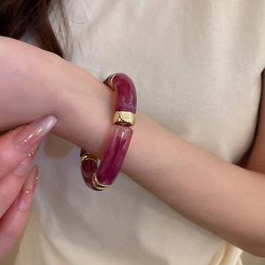 Detail of purple marble acrylic bracelet segments linked with golden metal rings