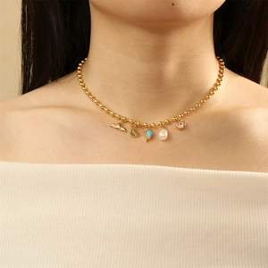 Detailed close-up of beaded necklace with pearl, zircon, and gold heart pendant on model