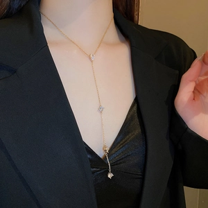 Élégant collier en Y doré avec quatre gouttes de zircon porté avec un tailleur noir chic
