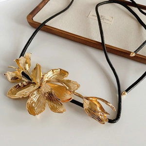 Macro view of metallic tulip flower pendant with detailed brushed texture and black cord