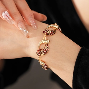 Close-up of vintage gold bracelet with red enamel flowers and sparkling crystals on wrist