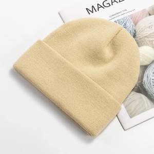 Detail of beige knitted beanie with rolled cuff on a stylish lifestyle background